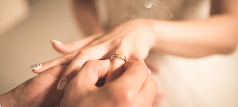 Groom putting a wedding ring on his bride